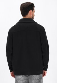 Sort uldblandingsjakke med spredt krave, knappede manchetter og lige snit. Har en glat tekstur og minimalistisk design.