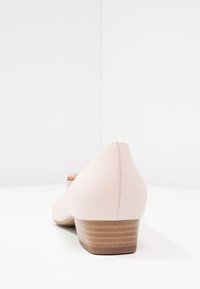 Vaaleanpunaiset ergonomiset kengät, joissa on matala puukorko, sileä pinta ja hienovaraiset rei'itetyt yksityiskohdat; pyöristetty kärki.