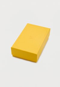 Ορθογώνιο κίτρινο κουτί με διακριτικό ανάγλυφο λογότυπο που απεικονίζει έναν κύκνο στο καπάκι, τοποθετημένο σε λευκό φόντο.