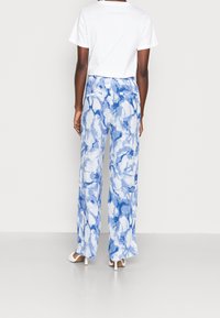 Pantalones de pierna ancha con un estampado azul y blanco, confeccionados con una tela ligera, que cuentan con una cinturilla ajustable y dos bolsillos traseros.