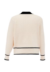 Tejelt, krémszínű kardigán bordás textúrával, fekete gallérral és szegélydíszítéssel. Apró lyukak találhatók rajta a légáteresztő képesség érdekében. Rövid, testhez simuló fazon.