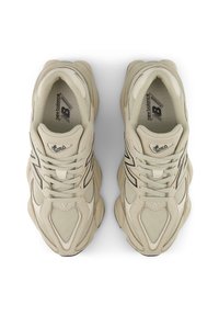 Baskets athlétiques beiges avec dessus en mesh texturé et cuir, comprenant des accents noirs, un bout rond et une semelle extérieure en caoutchouc robuste.