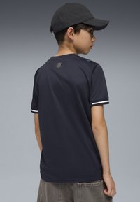 Marineblå sports T-shirt med korte ærmer, kontrasterende hvide striber på manchetterne og et logo på den bagerste halsudskæring. Casual fit, fugttransporterende stof.