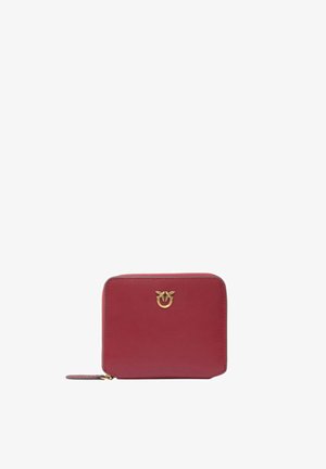 Piccolo portafoglio quadrato in pelle rossa con cerniera dorata e logo dorato a forma di uccello sul davanti su sfondo bianco.