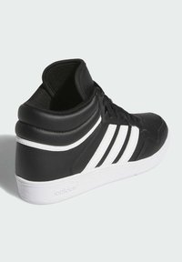 Czarne sznurowane trampki za kostkę wykonane z syntetycznej skóry z trzema białymi paskami. Posiadają białą gumową podeszwę oraz wyściełane wsparcie dla kostki.