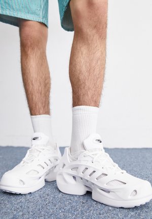 Witte sportieve schoenen met een bovenwerk van mesh, met uitsneden, veters en een dikke zool. Draag ze met witte crew-sokken en gestreepte shorts.