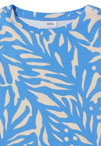 Tissu tropical à motif de feuilles bleu et beige avec un col rond et une étiquette "CECIL" cousue à l'intérieur du col.