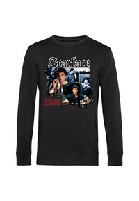 Felpa nera con diverse scene di un uomo dal film Scarface, inclusa una in cui è seduto a una scrivania mentre tiene un sigaro, con il testo "Scarface".