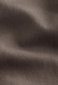 Close-up of brown fabric with fine diagonal weave texture and soft folds creating light and shadow variations.