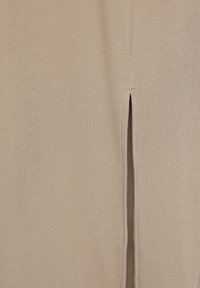 Tissu beige côtelé avec un détail de fente verticale. Texture lisse, avec une couleur neutre mettant en valeur les caractéristiques de design simples.