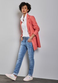 Koralli bleiseri, valkoinen paita, vaaleansiniset skinny-farkut ja vaaleanpunaisin yksityiskohdin varustetut valkoiset tennarit. Rennon tyylikäs asu, jossa on kerroksellisia tekstuureja ja hyvin istuva leikkaus.