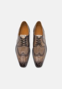 Scarpe eleganti in pelle marrone con dettagli brogue, punta affusolata e accenti perforati. Presentano lacci neri e una finitura liscia.