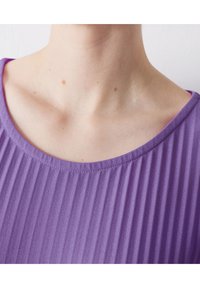 Lila strukturiertes Oberteil mit senkrechten Falten, einem abgerundeten Ausschnitt und glattem Stoff, der ein leichtes, weiches Erscheinungsbild betont.