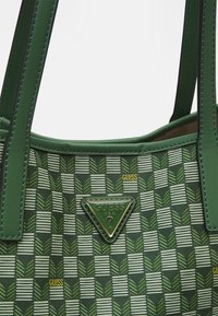 Borsa verde con un motivo geometrico a forma di foglia, caratterizzata da un logo triangolare dorato, materiale sintetico e cuciture nere a contrasto.