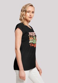 Zwarte T-shirt met een ronde hals en kapmouwen, voorzien van een kleurrijke kerstafbeelding met feestelijke figuren en tekst.