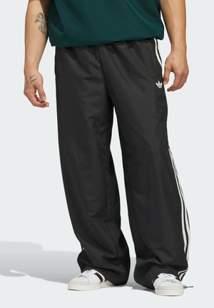 Crne sportske hlače od laganog, prozračnog materijala. Imaju bijele bočne pruge i izvezeni logo, s opuštenim krojem i elastičnom pojasom.