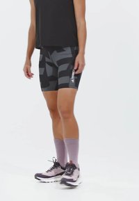 čierne a šedé šortky so vzorom a priliehavým strihom, doladené s levanduľovými ponožkami a svetlošedými športovými topánkami.