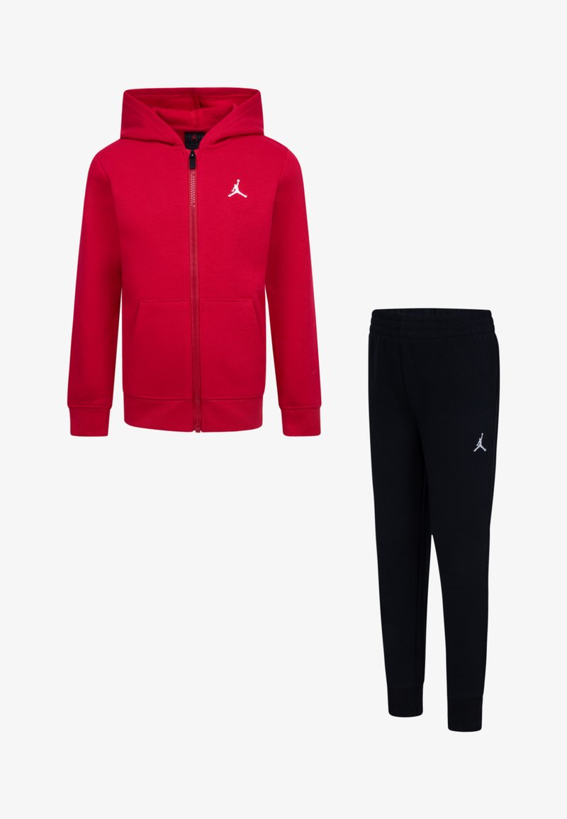 Rdeča zip-up kapuca z sprednjim žepom in logotipom, kombinirana z črnimi taper pants hlačami, ki imajo vezen logotip. Mešanica bombaža.