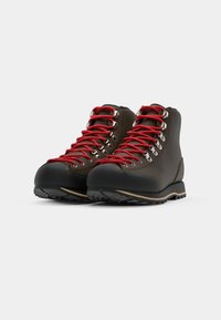 Brune turstøvler med sorte gummitåspidser, røde snørebånd, metaløjer og en struktureret sål til godt fodfæste. Casual men holdbart design.