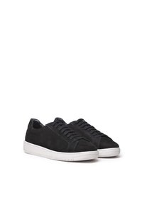 Mustad sägupärased mustad suedsneakerid tekstureeritud pinnaga, valge kummist tald ja lamedad paelad. Lihtne disain ilma nähtava brändimise või aktsentideta.