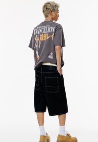 Harmaa puuvillapaita, jossa on Evangelion-kuvio selässä, yhdistettynä mustiin farkkushortseihin. Keltaiset mekko-kengät ja valkoiset sukat viimeistelevät asun.