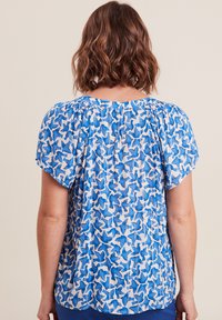 Korte mouwen blouse in blauw en wit met een herhalend bloemenpatroon, met een geraffineerd detail bij de halslijn en zacht, lichtgewicht stof.