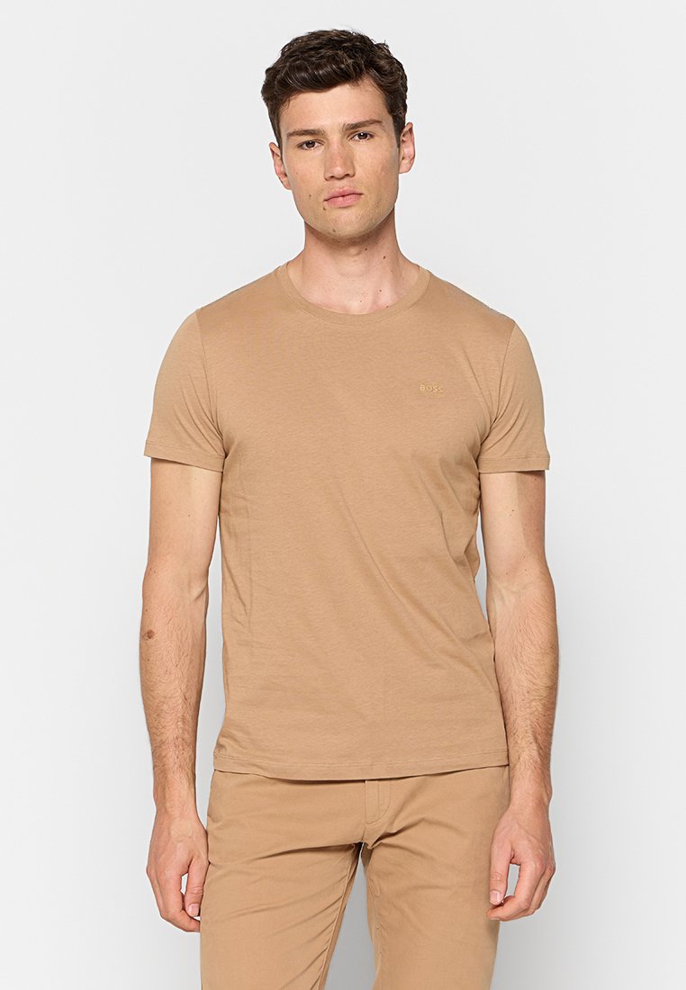 Beige Baumwoll-T-Shirt mit Rundhalsausschnitt und kurzen Ärmeln. Auf der linken Brust befindet sich ein kleines Markenlogo in einer helleren Farbe.