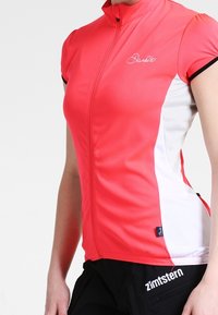 Rowerowa koszulka z krótkim rękawem w jaskrawym różowym kolorze z białymi bocznymi panelami, wyposażona w przedni zamek błyskawiczny, dopasowany krój oraz logo na piersi.