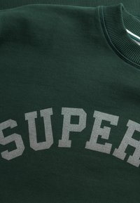 Zielona bluza z kapturem z dużym napisem "SUPER" w szarych blokowych literach na piersi, z prążkowanym dekoltem i miękką fakturą materiału.