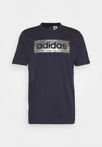 Camiseta de algodón azul marino de manga corta, con un logo metálico plateado centrado en el pecho, cuello redondo y diseño minimalista.