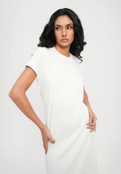 Vestito bianco a maniche corte con una vestibilità comoda e scollatura rotonda. Tessuto jersey morbido, tasche laterali e un leggero drappeggio accentuano la forma.