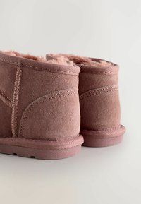 Rövid rózsaszín velúr bokacsizmák puha szőrme béléssel, varrott részletekkel és texturált gumitalppal.