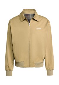 Smėlinis zip-up džemperis su smailiu apykakle, elastingomis rankovėmis ir plaid pamušalu. Kairėje krūtinės pusėje yra baltas adidas logotipas.