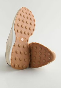 béžová sportovní obuv s texturovou gumovou podrážkou s hexagonálními vzory. Svršek je vyroben z měkkého materiálu s minimalistickým designem.