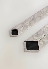 Grey tie with a floral pattern in a textured fabric, featuring a solid black underside and angled tips, showing clean, elegant lines.