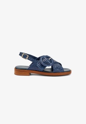 Sandale en cuir tressé bleu marine avec une grande boucle circulaire, une bride de cheville ajustable, une semelle intérieure noire rembourrée et un petit talon en bois.