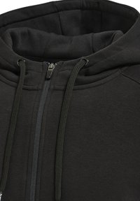Schwarze Zip-Hoodie mit gefütterter Kapuze, ausgestattet mit Kordelzügen und einem dezent strukturierten Stoff. Reißverschluss vorne.