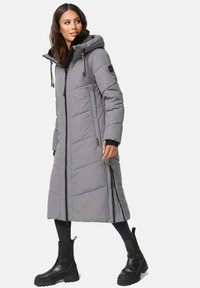Long gray puffer coat with a hood, zippered front, side pockets, and a textured pattern. Paired with black ankle boots.