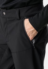 Pantalones funcionales negros que cuentan con un bolsillo con cremallera, cierre de botón y costuras estructuradas para un ajuste a medida. Elaborados con material ligero y transpirable.