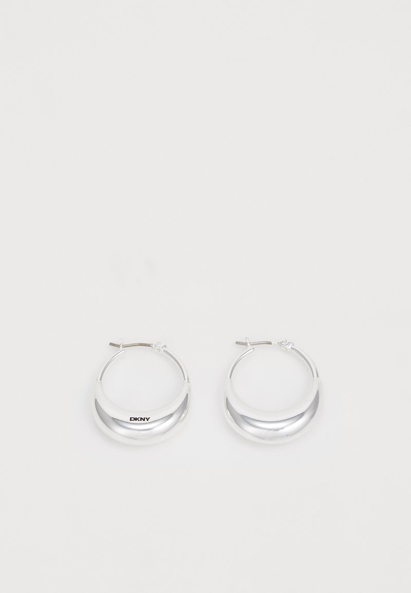Pendientes de aro de plata con un acabado pulido y la marca DKNY, exhibidos sobre un fondo blanco liso.