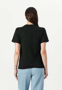 Zwarte katoenen t-shirt met korte mouwen en een ronde hals, met een effen achterkant en een relaxte pasvorm, gecombineerd met lichtblauwe jeans.