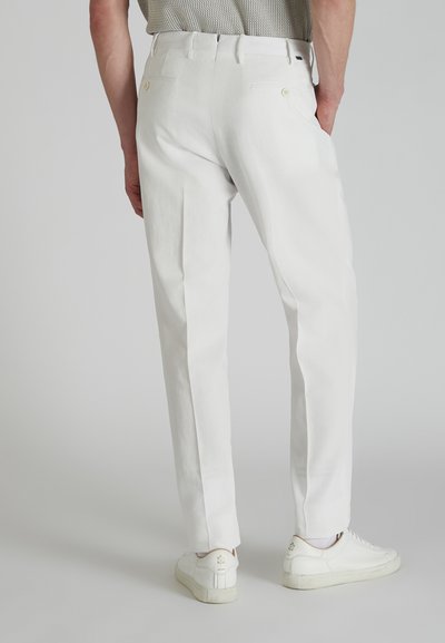 Pantalones blancos ajustados con una tela suave, con dos bolsillos traseros y un diseño de pierna recta. Combinados con zapatillas blancas.
