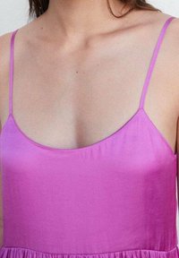 Top sans manches en satin rose vibrant avec une texture lisse et un léger éclat. Doté de fines bretelles et d'une coupe décontractée et fluide.