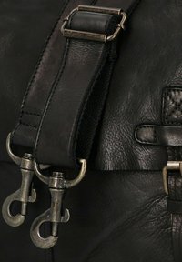 Zwarte leren tasriem met een getextureerd lichaam, voorzien van zilveren metalen clips en verstelbare onderdelen voor lengtemodificatie.