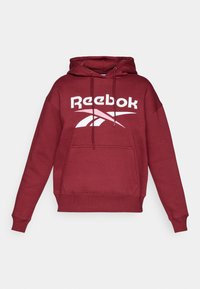 Felpa con cappuccio color marrone scuro realizzata in misto cotone, caratterizzata da un grande logo Reebok bianco, tasca a marsupio e polsini e orlo a coste.