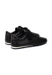 Baskets en cuir noir avec une finition lisse, design à lacets, accents cloutés sur le talon et une semelle blanche contrastante.