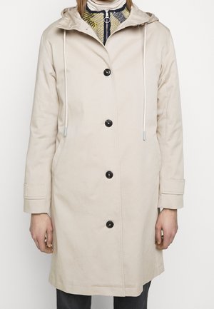 Beiger leichter Mantel mit Kapuze, ausgestattet mit einer Knopfleiste, zwei seitlichen Taschen und Kordelzügen an Kapuze und Ärmelbündchen.