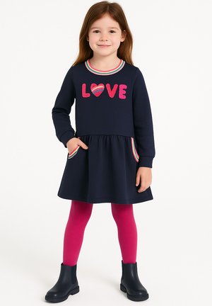 Marineblaues Kleid mit langen Ärmeln, das mit pinkem "LOVE" und Herzstickereien, gestreiftem Kragen und Taschenakzenten versehen ist, kombiniert mit pinken Leggings und schwarzen Stiefeln.