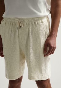 Bermude crem dintr-o stofă de terasă texturată, având un model geometric, talie elastică cu șnur și buzunare laterale.