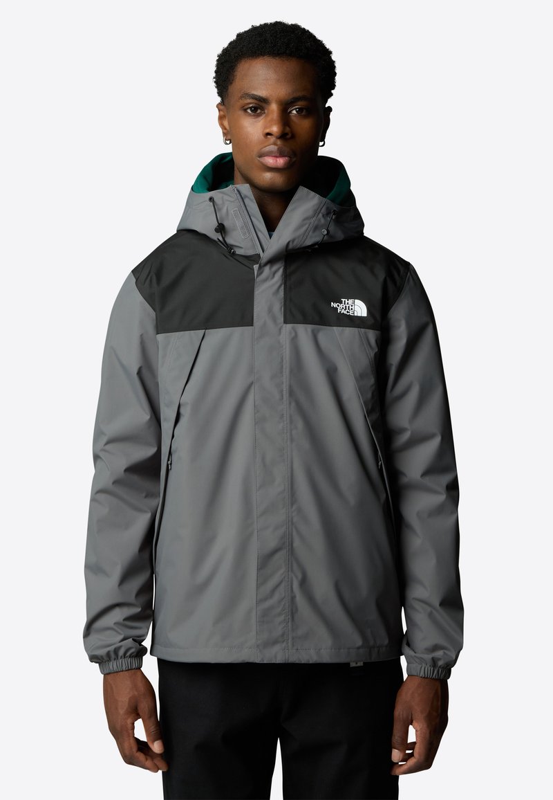 Grijze waterdichte jas met zwarte schouderpanelen, verstelbare capuchon, elastische manchetten en voorzakken met ritssluiting. Voorzien van het logo van The North Face.